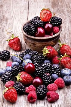 berries and strawberries in a bowl on a wooden table