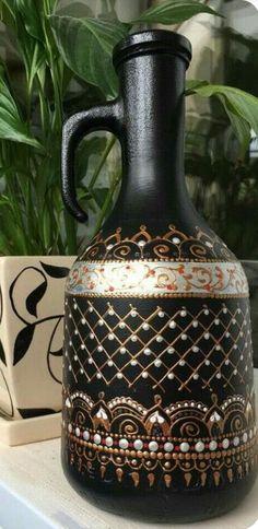 a black vase sitting on top of a white shelf next to potted plants and a planter