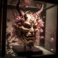 a mask with horns and flowers on display in a glass case