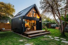 a small black house sitting on top of a lush green field