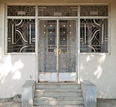 the front door to an old building with wrought iron doors and steps leading up to it