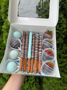 a person holding a box full of chocolate covered strawberries