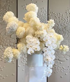 a white vase filled with lots of white flowers