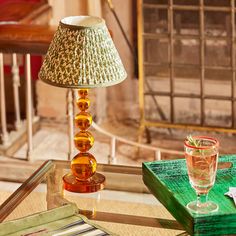 a glass table with a lamp on top of it next to a green tray and napkins