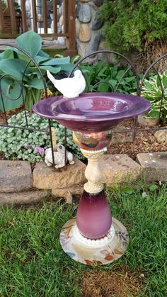 a bird bath sitting on top of a purple plate