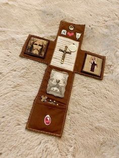 a cross made out of brown leather with pictures on the front and back, sitting on top of a white rug