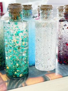 four bottles filled with glitter sitting on top of a table