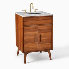 a wooden sink cabinet with two brass faucets and a marble counter top on one side