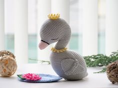 a crocheted bird sitting on top of a table next to a vase with flowers