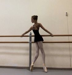 a young ballerina is practicing her moves on the ballet bar in an empty room