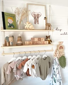 a baby's clothing rack with clothes hanging on it and an elephant toy next to it