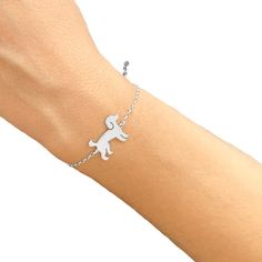 a person wearing a bracelet with a dog charm on it's wrist and holding onto the