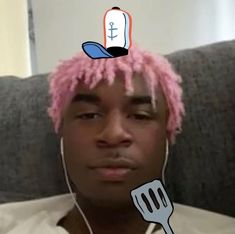 a man with pink hair has a fork in front of his head and is listening to music