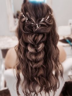 the back of a woman's head with long, curly hair in a half - up braid