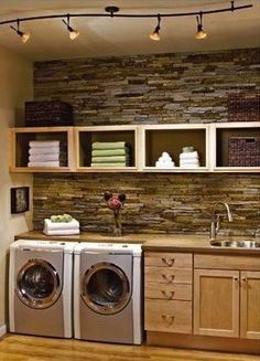 a washer and dryer sitting in a kitchen next to cabinets with towels on them