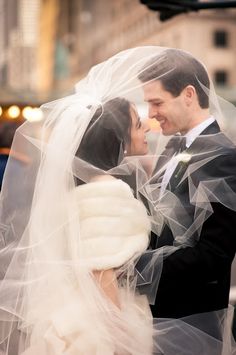 a bride and groom standing under a veil in the street with traffic lights behind them