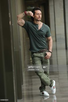 a young man leaning against a wall in an empty building with his hand on his head