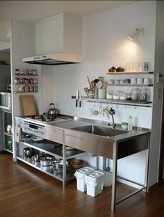 a kitchen with stainless steel sink and shelving units on the wall above it is filled with pots and pans