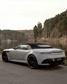 a white sports car parked in front of a lake