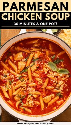 a pan filled with pasta and chicken soup on top of a wooden table next to corn