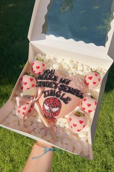 someone is holding up a box filled with valentine's cookies and marshmallows