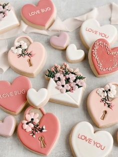 heart shaped cookies decorated with love bugs and flowers are arranged on a white tablecloth