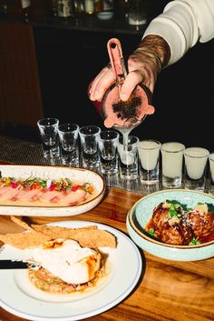 a person is pouring something into a glass at a table with plates and glasses on it