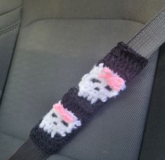 a crocheted cat sitting in the back seat of a car with its head down