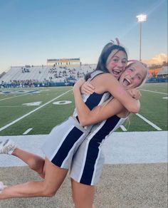 two girls hugging each other on a football field