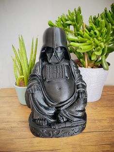 a statue of darth vader sitting on top of a wooden table next to potted plants