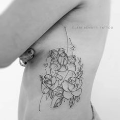 a woman's stomach with flowers and leaves tattooed on her side, in black and white