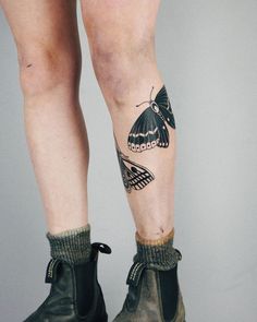 a woman's legs with tattoos on them and boots in the shape of butterflies