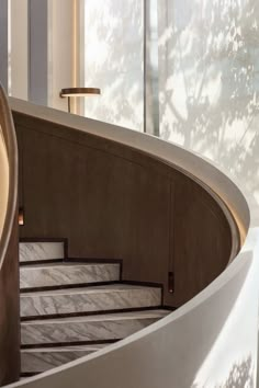 a spiral staircase with marble steps in front of a window