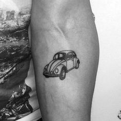 a black and white photo of a car tattoo on the left arm, next to a woman's leg