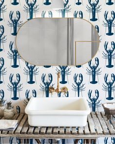 a bathroom sink sitting under a mirror next to a wall mounted faucet in front of a blue cactus pattern