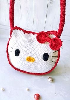 a crocheted hello kitty purse sitting on top of a white table next to candy