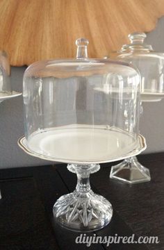 two clear glass dishes sitting on top of a black table next to a wooden wall