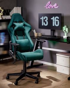 a green office chair sitting in front of a desk with a computer monitor and keyboard