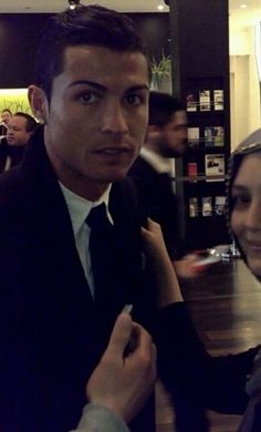 a man in a suit and tie standing next to a woman at a table with other people