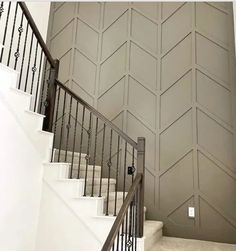 a stair case next to a wall with chevron panels on it and a door in the middle