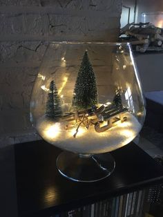 a glass bowl filled with water and christmas trees in the center, on top of a table