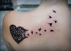 a woman's back with black birds flying around her and a lace heart tattoo on it