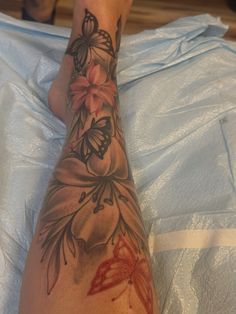 a woman's foot with flowers and butterflies tattooed on the side of her leg