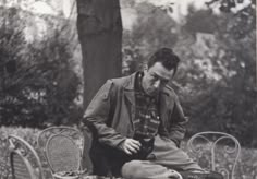 black and white photograph of a man sitting on a bench with his foot in the ground