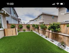 a backyard with artificial grass and wooden fenced in area next to the house on a cloudy day