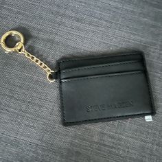 a black leather card case with a gold chain hanging from it's front pocket