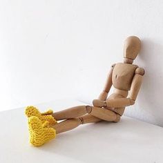 a wooden mannequin sitting on top of a white table next to a yellow stuffed animal