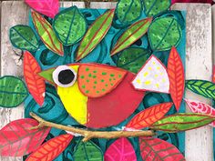 a colorful bird sitting on top of a tree branch surrounded by leaves and flowers in front of a wooden fence