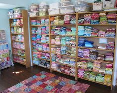 a room filled with lots of different types of fabrics and quilts on shelving