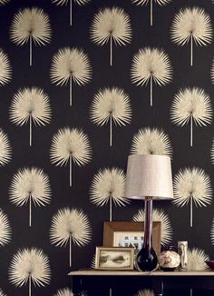 a black and white wallpaper with dandelions on the side table next to a lamp